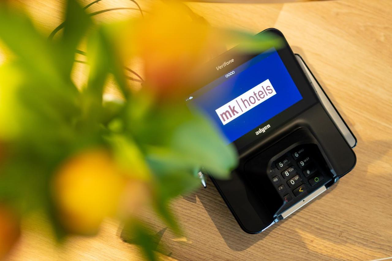 Mk Hotel Tirana Rinas エクステリア 写真 A mobile phone with the MK1Hotels logo on the screen